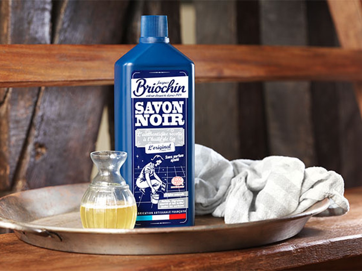 Flacon de savon noir Briochin sur un plateau en métal avec une carafe d’huile et un linge en coton