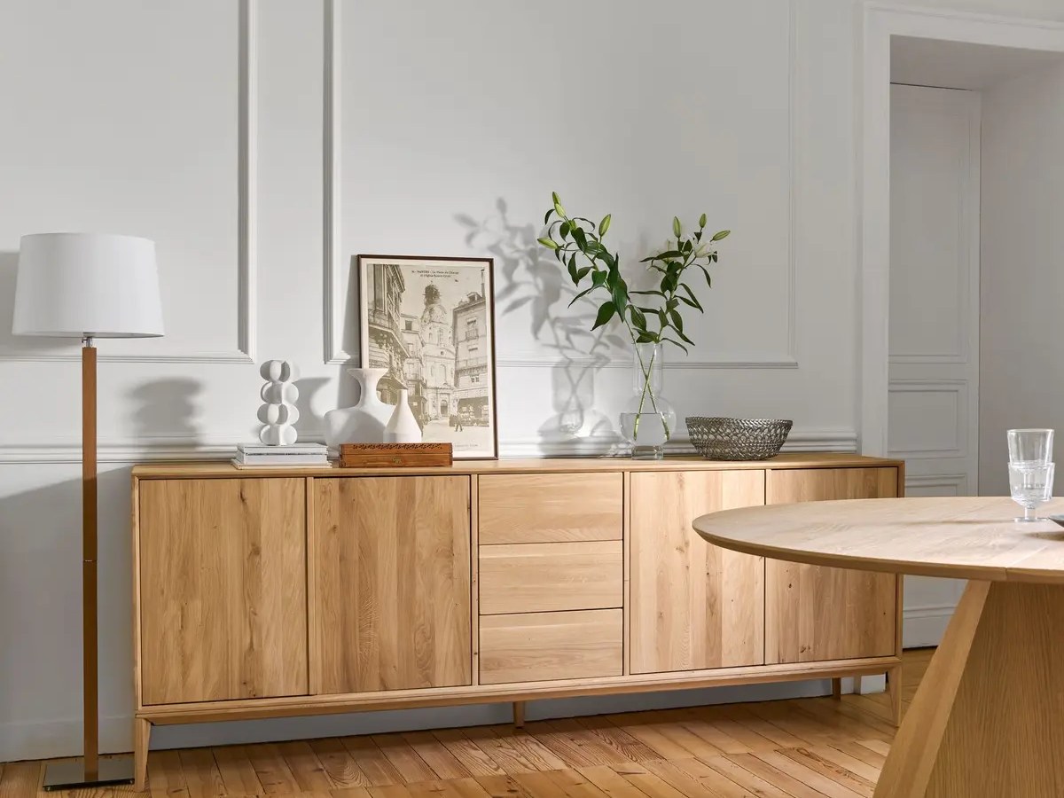 Grand buffet en chêne clair et table ronde en bois dans un séjour haussmannien aux murs blancs