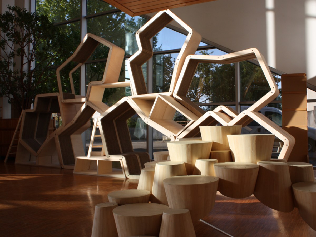 Structure et mobilier en bois clair exposés dans un hall vitré baigné de lumière