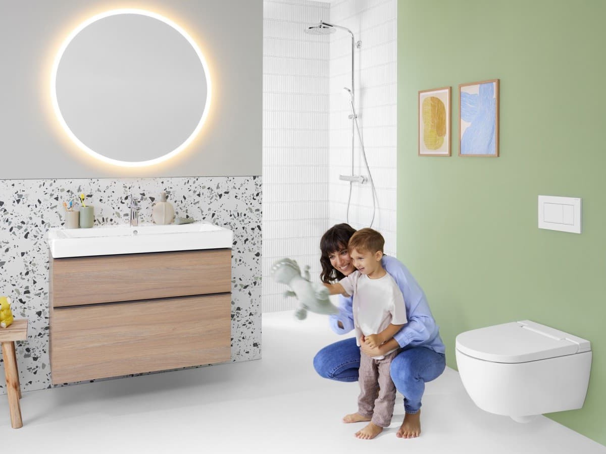 Salle de bains lumineuse Geberit avec meuble lavabo en bois, miroir rétroéclairé et WC suspendu