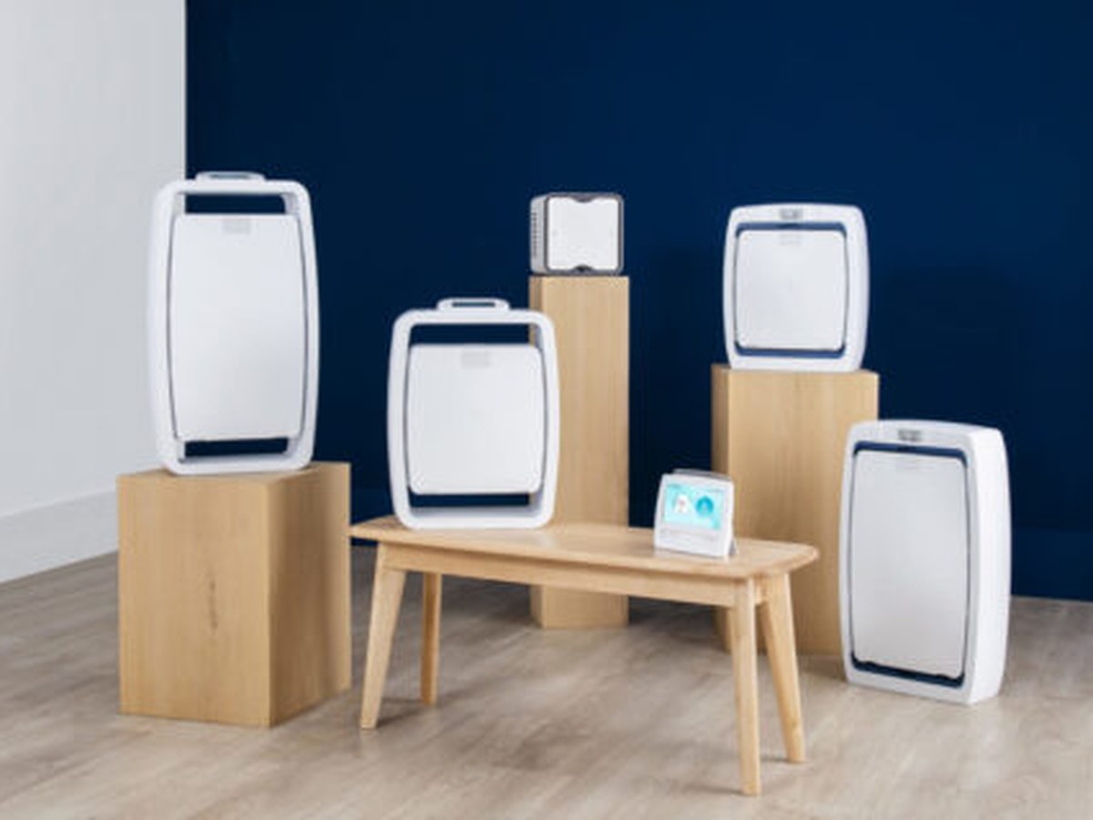 Gamme de purificateurs d’air NatéoSanté présentée sur des socles en bois clair devant un mur bleu nuit