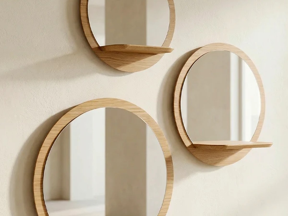 Trois miroirs ronds en chêne clair avec tablette intégrée, accrochés sur un mur ivoire