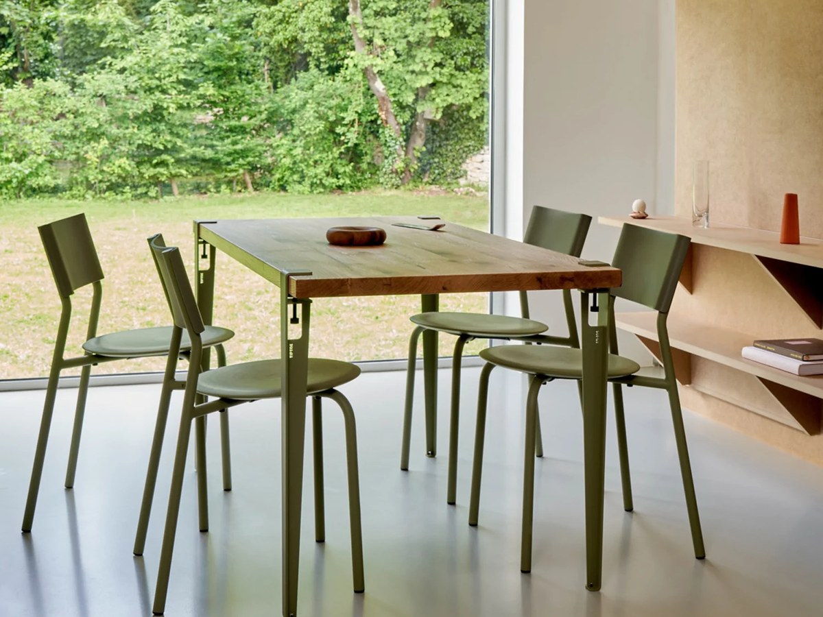 Table en chêne et chaises TIPTOE vert olive devant une grande baie vitrée ouverte sur un jardin