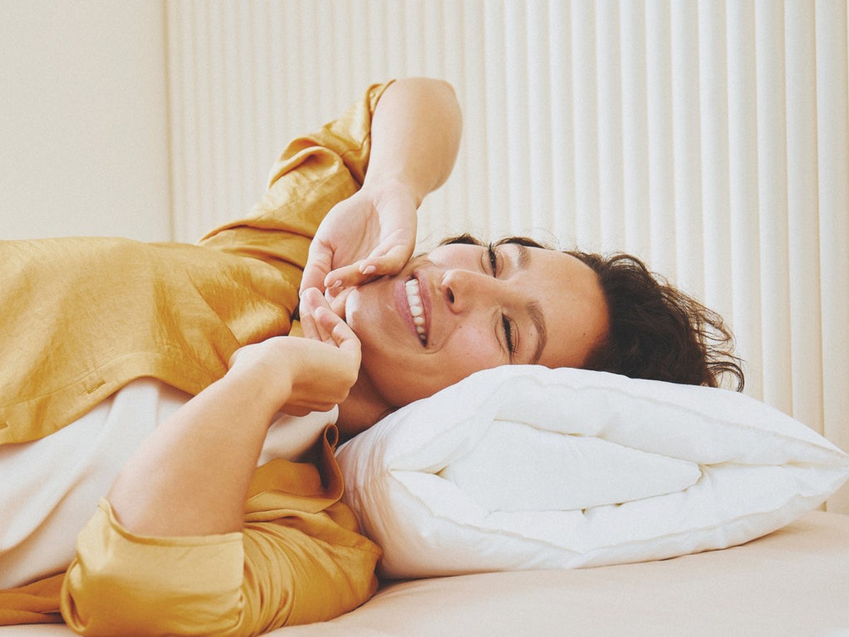 Femme souriante allongée sur un oreiller Wopilo dans une chambre très lumineuse