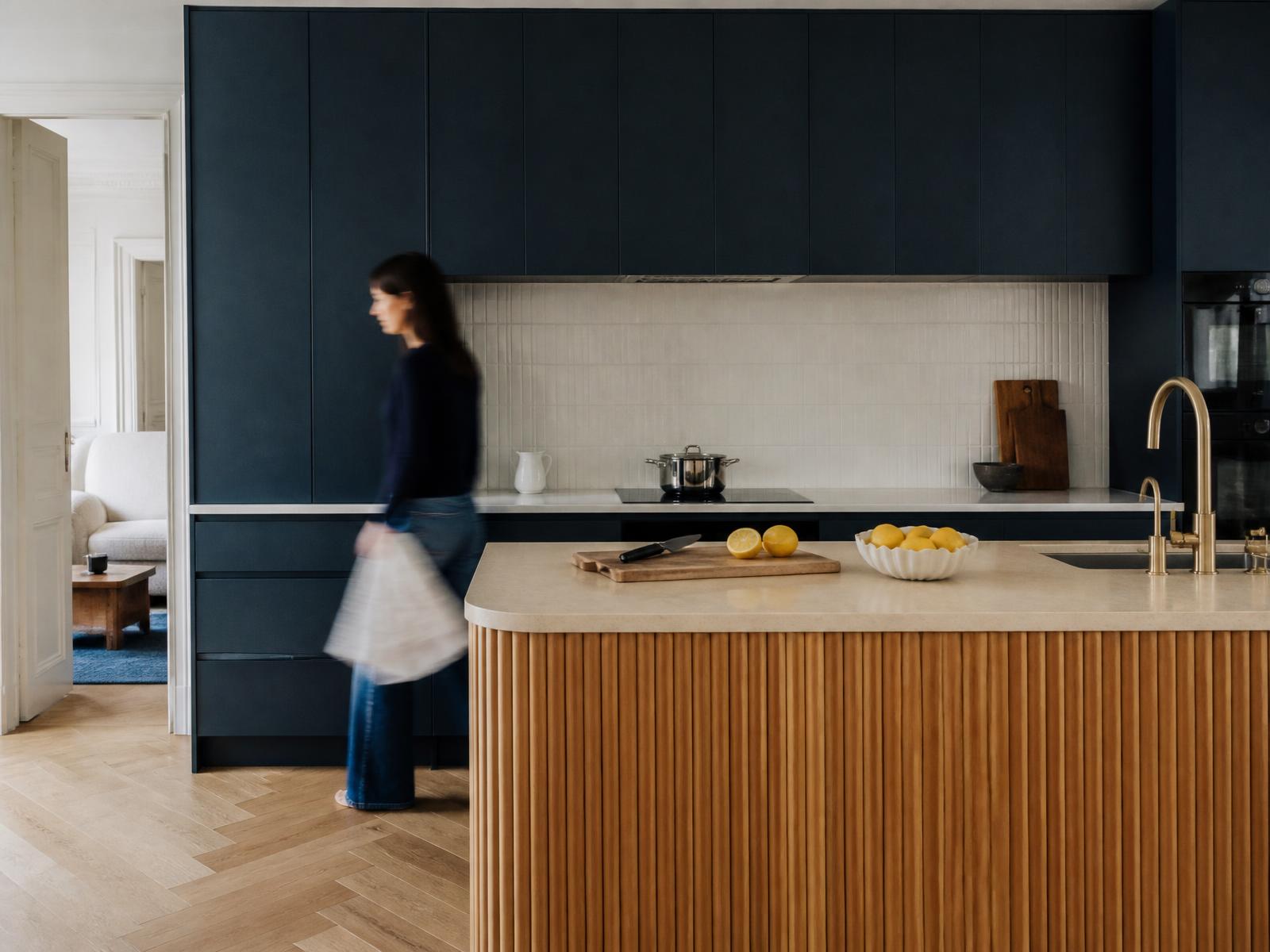 Cuisine contemporaine à façades bleu mat, îlot en chêne cannelé et présence en flou de mouvement
