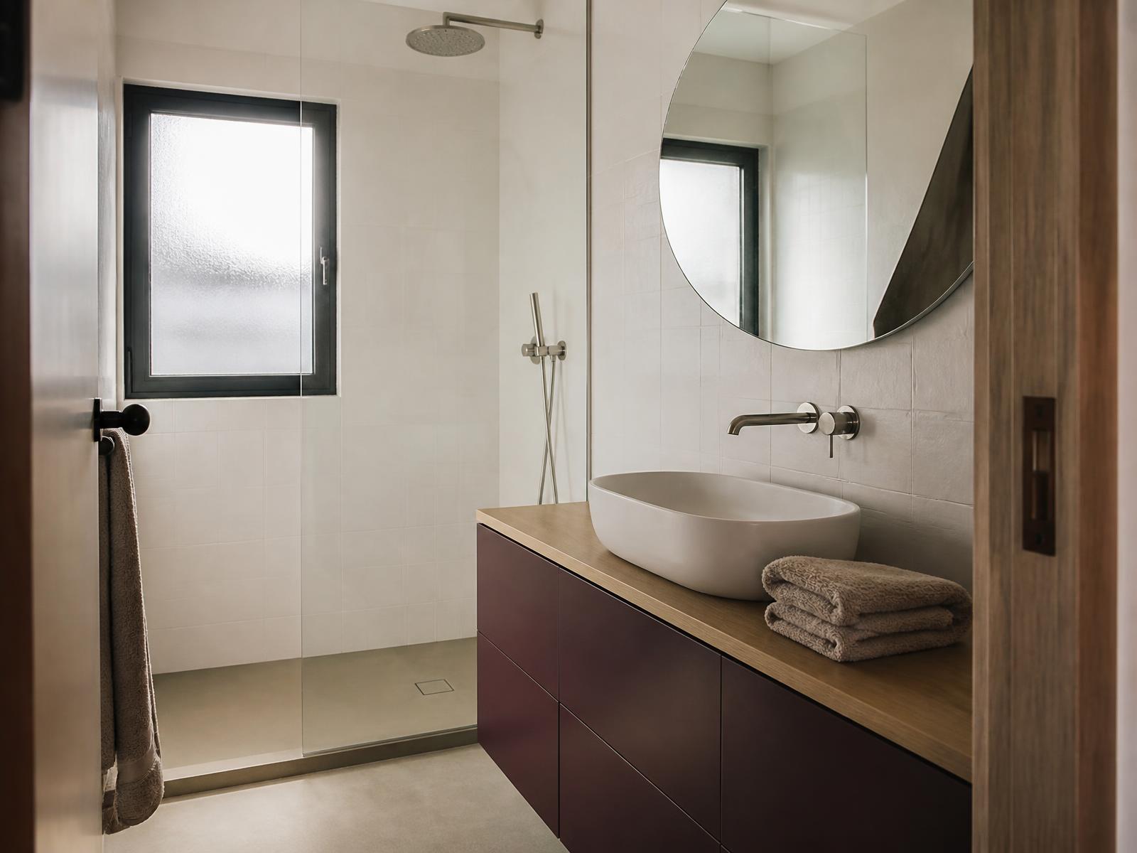 Salle de bain moderne avec meuble à façades prune mates, plan en chêne et douche à l’italienne